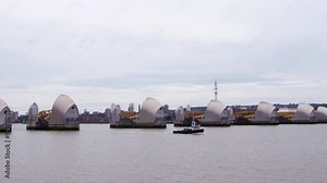 Small boat passing the river Thames barrier, London. It is a barrier to regulate the tide of the river and avoid flooding