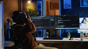 Teleworking programmer using futuristic VR glasses in home office to do javascript programming. IT expert wearing high tech virtual reality headset to visualize lines of code, camera A