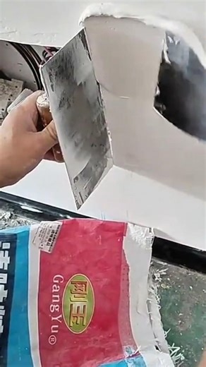 applying smooth white plaster on a concrete wall surface using a manual metal trowel for finishing