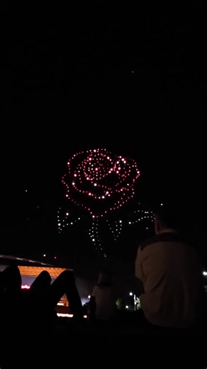 Witnessing this spectacle felt like stepping into a sci-fi movie! 🤯 Hundreds of illuminated drones assembling into a colossal, perfectly detailed 3D rose against the inky black. The vibrant red petals and glowing white stem create a breathtaking contrast. This cutting-edge drone art show turns the atmosphere into a living canvas of light and motion. Pure wonder captured from the crowd's perspective! ✨🌹 #DroneShow #LightArt #3DRose #SkyArt #TechMagic