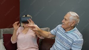 Enthusiastic grandfather and grandmother with VR headset helmet play games, watch virtual reality 3D 360 video. Family of senior man and woman at home. Future technology. VR goggles, glasses
