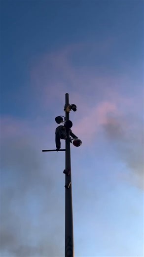 An anti-fascist Spider-Man is climbing a pole and disabling the camera.