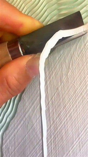 Carving wavy decorative patterns on a light green surface with sharp metal knife to create textures