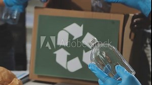 Garbage separation concept. Female hands separate paper and plastic into separate containers in the kitchen at home. Waste segregation, waste sorting, waste recycle.