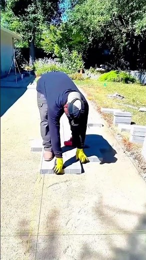 Laying interlocking paver blocks carefully along the measured lines for a straight pathway