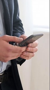Close up shot of a Caucasian male freelancer texting online, surfing web or net using smartphone. Remote communication concept. Vertical video.