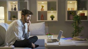 Man biting his nails because of stress at home at night.