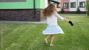 A beautiful young woman in a skirt is spinning on the lawn