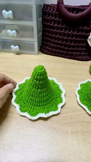 A cozy handmade crochet Christmas tree with layered green branches trimmed in white yarn, sitting beside a cute crochet Santa face ornament on a wooden table. Perfect for festive home decor and DIY holiday crafts. 🎄🧶✨ #CrochetChristmas #HandmadeHoliday #DIYDecor #FestiveCrafts #CozyCreations | thatlawndude