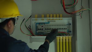 Download Electrician using electric screwdriver tester to check electric current in control box in home electrical installation and safety concept for free