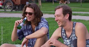 Two friends laughing and drinking while sitting in a park - slow motion - shot on RED