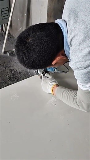 cutting large grey stone floor tiles manually using a blue electric handheld grinder machine outdoor
