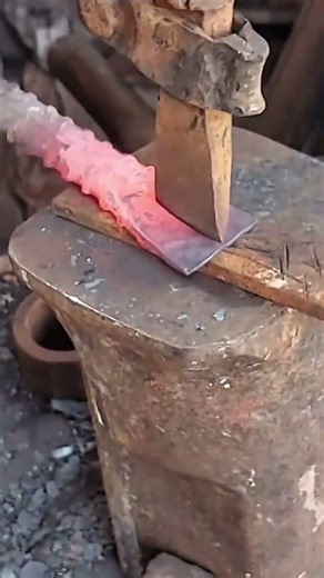cutting glowing hot metal using chisel tool on iron anvil for shaping the sword blade precisely