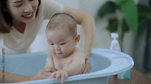 Young mom shower baby , Baby asian happy moment with mom at living room. asian family with newborn