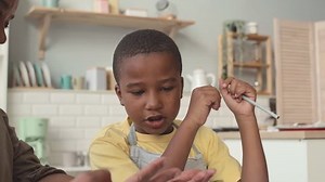 Smart African American 8 year old boy doing Math calculations while studying with grandma at home