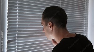 Paranoid man, Spy, journalist or detective, watches through the blinds