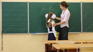 Girl and teacher near chalkboard solve simple math examples