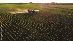 Aerial video of tractor spraying soil and young crop in springtime in field. Tractor spraying pesticides on soy field with sprayer at spring. Nozzle of the tractor sprinklers sprayed, machine concept. Stock Video