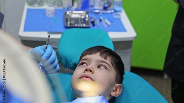 kid in dental office. dentist checking child teeth using tools mouth mirror and scalar.crying with tears, sad boy is afraid.doctor looking at screen,tooth filling treatment.kid in chair being examined