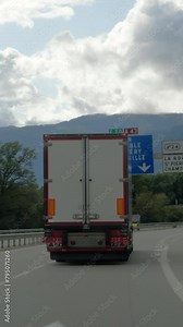 Vertical video of a cargo truck on a highway with directional signs for French cities overhead