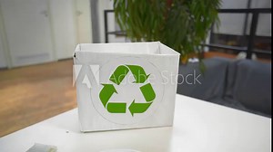 An unknown girl puts things in a cardboard box marked as recyclable. Close-up of a woman's hand throwing various electronic devices, batteries into a sorting box. Ecology and nature conservation