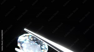 Loose diamond in tweezers selective focus. Macro shot of precious stone inspection for defects. Certification of brilliant cut diamond. Gemstone in clamp for making luxury jewelry. Natural material.