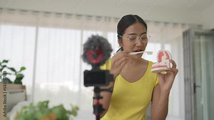 asian woman using toothbrush cleaning a mock up teeth and mouth. Dental teaching by video online e learning.