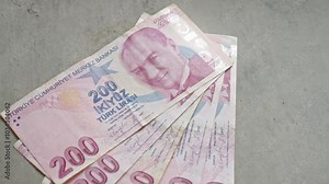 Turkish 200 lira banknotes spread out on a concrete surface, showcasing currency from turkey with detailed print and security features.