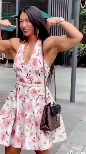 a beautiful muscular woman flexing front double biceps in dress