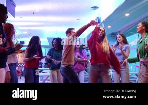 Friend group dancing, clapping, and celebrating together on bowling alley dance floor with vibrant energy and joyful connection during weekend nightlife moment Stock Video Footage - Alamy