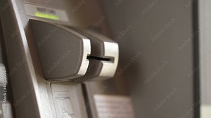 Detail of a man's hand inserting and removing a bank card at an ATM.