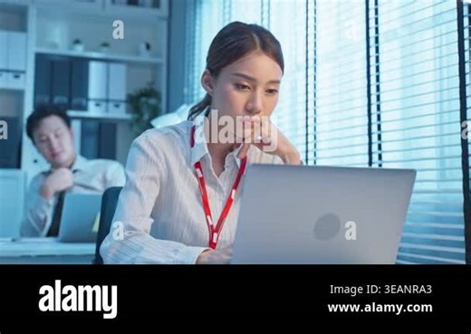 Young woman working on laptop at desk in a bright, modern office environment Stock Video Footage - Alamy