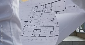 Architect precisely reviews paper with plan of vision contents of project closeup. Professional compares drawing of building with construction