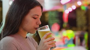 Woman drinks draft beer in pub closeup. Young lady with dark hair takes sip of fresh lager resting alone in bar. Pretty guest with alcoholic beverage