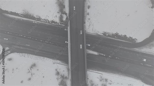 4K 60fps aerial static top view of a highway cloverleaf interchange in winter fog, cinematic grainy atmosphere.