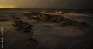 Time lapse of the beach at night with a high tide on the rocks