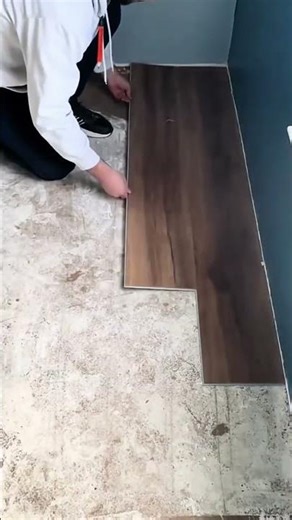 Man installing dark brown click lock vinyl plank flooring