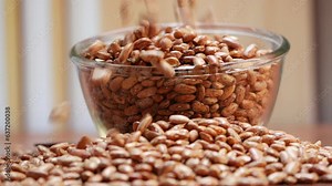 There are roasted peanuts, falling peanuts, and peanuts on a table