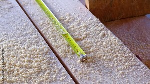 Measuring yellow tape measure scale with centimeters on wooden boards for marking the place of cutting. Lumber, house construction, carpentry. Slow Motion