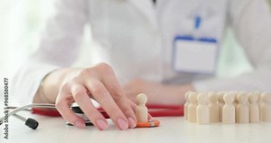 Doctor holds life preserver with wooden figures depicting patients in clinic