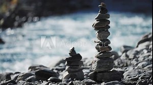Detailed footage of rock stacks on a riverbank, with flowing water creating a serene atmosphere.