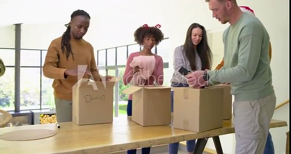 Tablet briefing guiding diverse volunteers folding items and sealing Donate boxes at kitchen table