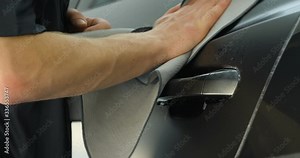 Close up of paint protection film installation on modern luxury car. PPF is polyurethane film that wrap car paint to protect paint surface from stone chips, bug splatter, and abrasion.