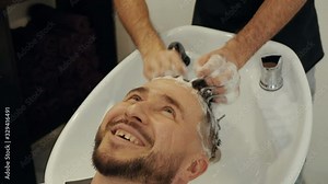 Hairdresser hand washing head of happy man in male salon. Hair stylist washing male head with shampoo in barbershop. Bearded man getting wash hair in barber salon Stock Video