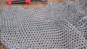 Young man make medieval chain armor with modern tools