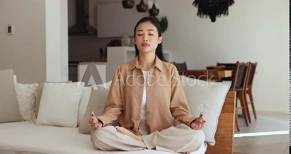 Woman meditate sit on sofa in lotus position with eyes closed. Female reducing stress by calming mind, boost emotional wellbeing, perform daily routine, keep healthy life habit. Rest, spiritual growth