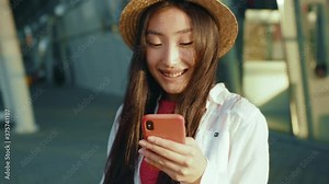Attractive chinese woman smiling using cellphone communication searching places in navigation map walking outside airport. Beautiful asian girl. Traveler. Business trip.