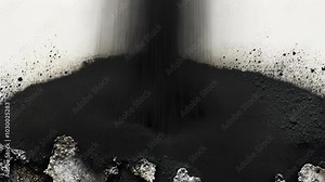 Black powder falls onto a white surface, creating a dark, dramatic pile