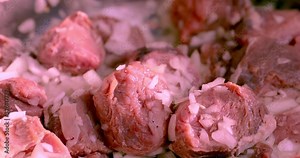 A pile of red raw beef meat rotates in a metal container