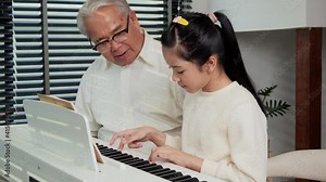 Grandfather looking granddaughter playing piano at living room. She was showing play piano to Grandfather with confident.